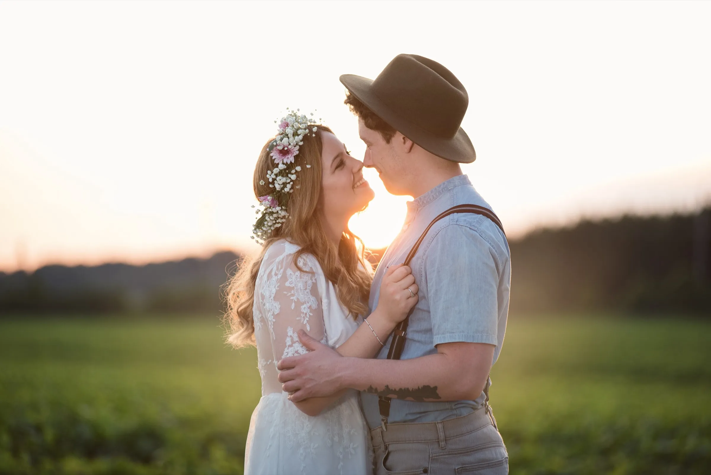 Casal se beijando ao pôr do sol em um campo
